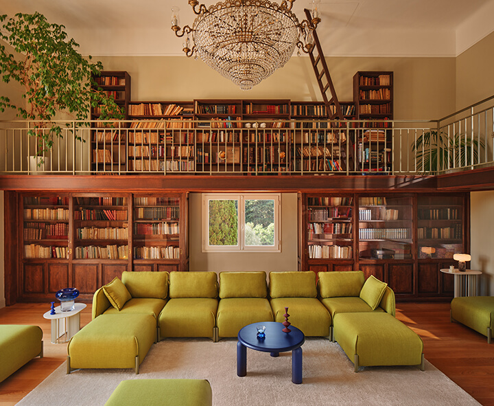 Nowoczesna przestrzeń coworkingowa wyposażona w meble biurowe, regały i kolorowe pufy.