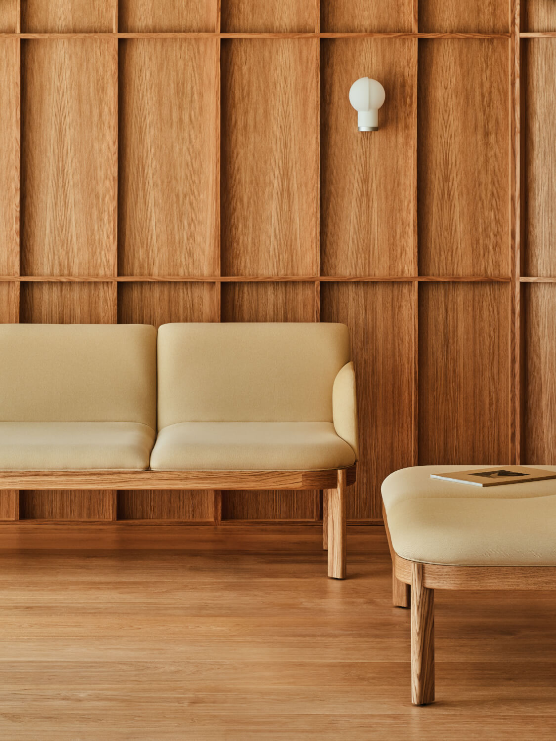 Jasnożółta sofa tapicerowana ustawiona na tle drewnianej ściany