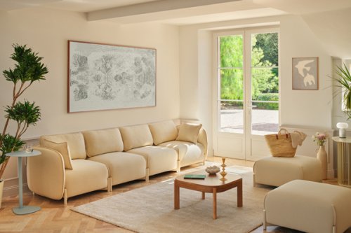 Meble w jasnym salonie - beżowa sofa, stolik i fotel przy dużym oknie